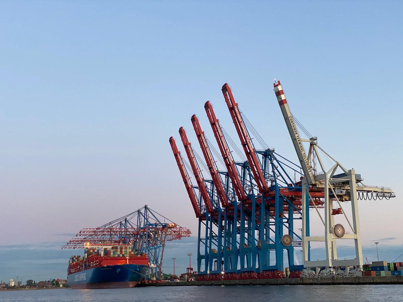 Red gantry crane above stacked shipping containers at a port terminal